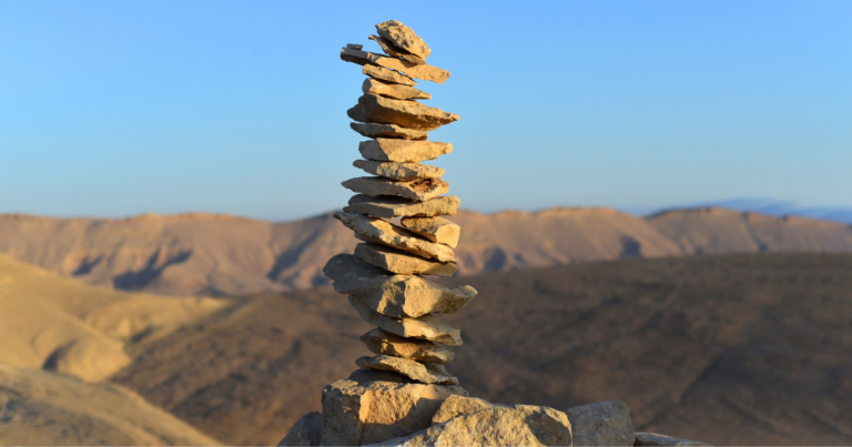 Stone cairn in desert symbolizing structured trust and shared leadership foundation